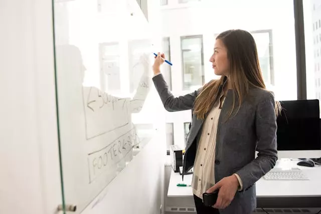 Image of a women writing in a whiteboard